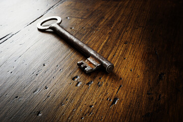 Answer, guess, solution to a problem concept. An old metal key lies on a wooden surface.