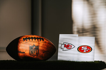 Naklejka premium American Football Ball on green Grass and logo of NFL and teams Kansas City Chiefs vs. The San Francisco 49ers. Two Finalists of Super Bowl LVIII in Las Vegas, Nevada