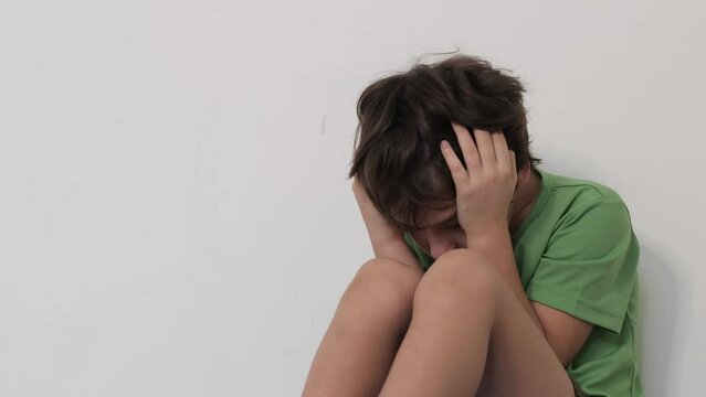 Small child in a protective pose, concealing his face from the world, indicative of deep emotional distress or social anxiety. Can illustrate child welfare articles or mental health awareness