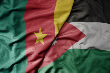 Obraz premium big waving national colorful flag of jordan and national flag of cameroon .