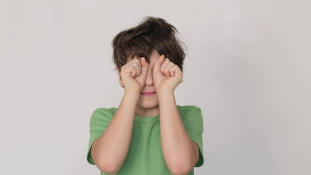 Young boy massaging his eyelids, depicting a common reaction to exhaustion or overuse of digital devices. Ideal for articles on screen time limits.