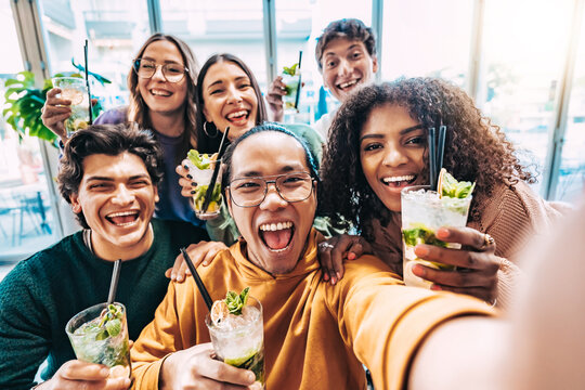Multiracial friends drinking and toasting cocktail mojito at bar - Group of happy young people taking selfie picture at restaurant - Life style concept with youth guys enjoying happy hours