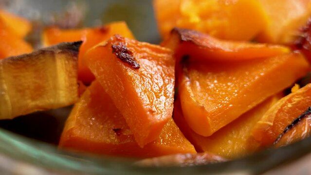 Oven baked pumpkin slices. Roasted Butternut Squash pieces close up. Rotation