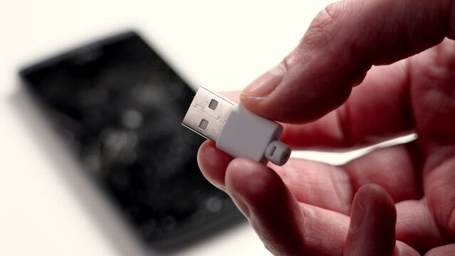Broken USB plug torn from the cable with a smartphone on a white background. Connect problem concept