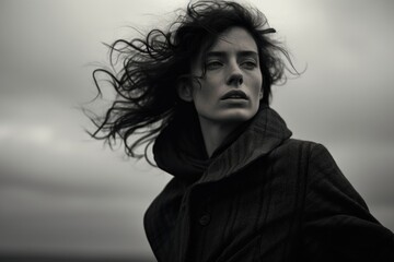 A black and white photo capturing a woman with her hair blowing in the wind. This image can be used...