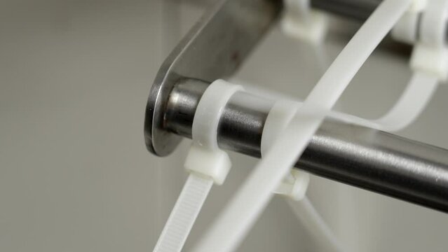Removing by cutting off attached plastic cable ties  from a metal structure with a utility knife close up