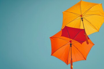 Fototapeta na wymiar Upward view of two orange umbrellas under a clear blue sky, abstract and minimalist design concept