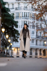 Fashion-forward woman strolls confidently on a city street, dressed in a chic winter outfit. 