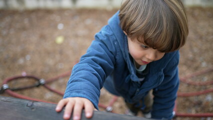Happy active child climbing playground ropes during fall season. Autumn day play of 3 year old boy...