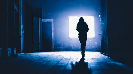 Silhouette of a lonely woman at night in a dimly lit location