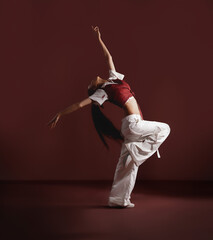 Traditional Dancer Showing Dance Step In Isolated Maroon Background, spreading hand like jumping...