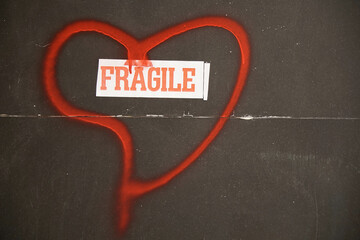 Fragile text inscribed in a hand-painted red heart