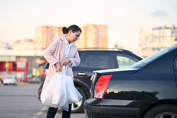 young woman has done her shopping after work and loads packages into her car