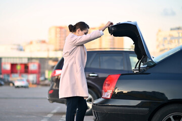 woman is about to close the trunk of her sedan