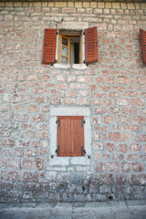 Fototapeta na wymiar Windows with shutters on an old stone wall, Montenegro.
