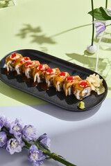 Summery sushi concept with eel roll, tobiko caviar, and unagi sauce amidst pastel floral decor