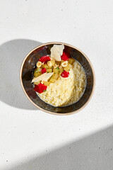 Top view of millet porridge with stewed pear in a rustic bowl, bathed in morning light