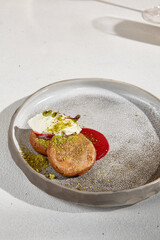 Close-up View of Syrniki with Sour Cream and Fruit Sauce on a Modern Plate.