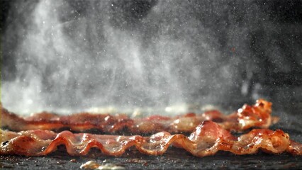 The bacon is fried in a pan with a splash of oil. Filmed on a high-speed camera at 1000 fps. High quality FullHD footage