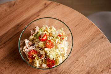 Dining table with vegetable diet salad with chicken in a glass bowl in a modern kitchen