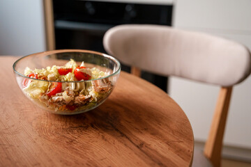 Dining table with vegetable diet salad with chicken in a glass bowl in a modern kitchen