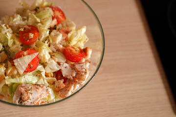 Dining table with vegetable diet salad with chicken in a glass bowl in a modern kitchen