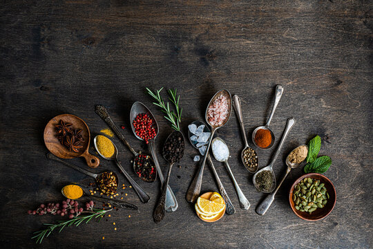 Assorted spices and seeds in spoons on a wooden background
