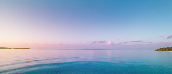 wide sunrise or sunset panorama of tropical island beach, seascape with wide horizon showing beautiful calm sky meeting sea