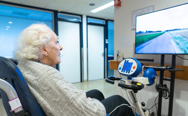 Senior woman doing rehabilitation with a stationary bike in a nursing home