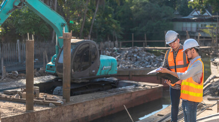 Construction engineer working on a bridge construction site over a river,Civil engineer supervising work,Foreman inspects work at a construction site,Discuss technical problems together