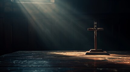 Holy cross, crucifix standing next to a bible on a dark background with rays of light directed from...