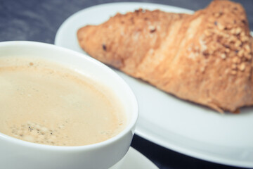 White cup of coffee and fresh croissant with chocolate