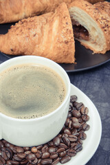 Breakfast consisting of fresh croissant with chocolate and coffee in white cup