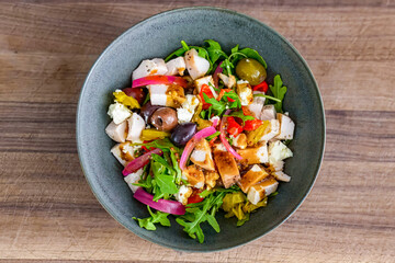 Healthy fresh salad with vegetables, chicken on plate. Homemade delicious lunch with chicken, bell pepper, olives, arugula for restaurant, menu, advert or package, close up selective focus. Top view.