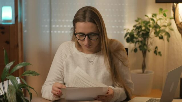 A woman, a girl in glasses looks through papers, documents and puts a folder with documents. Home office, accounting department