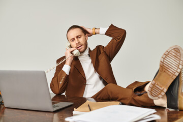hard working elegant male model in stylish suit talking by vintage phone with legs on table