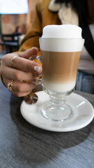 imagen vertical mano de mujer sostiene taza de café capuchino