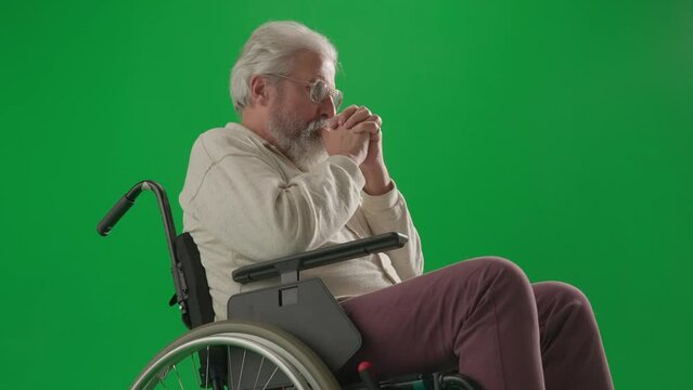 Portrait of aged man on chroma key green screen. Close up senior man sitting in wheelchair thinking, upset depressed expression.