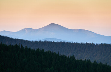 Meeting sunrise in Carpathian mountains. Early morning in forest. Beautiful dawn over hills.