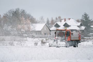 Road maintenance in winter. a tractor equipped with a spreader sprays a salt and sand mixture on the icy and snowy road. The vehicle belongs to the municipal service that melts the snow