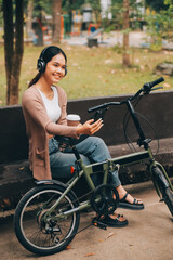 Happy young Asian woman while riding a bicycle in a city park. She smiled using the bicycle of transportation. Environmentally friendly concept.