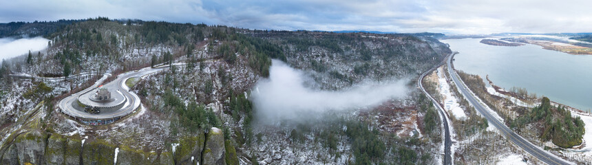 A light dusting of snow covers the Columbia River Gorge near the Crown Point Vista House. This scenic area, not far east of Portland, Oregon, is full of waterfalls and epic outdoor scenery. - obrazy, fototapety, plakaty