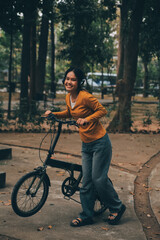 Obraz premium Happy young Asian woman while riding a bicycle in a city park. She smiled using the bicycle of transportation. Environmentally friendly concept.