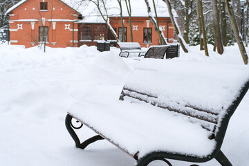 Winter in the city park. Benches in the snow, selective focus