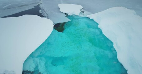 Melting arctic blue water glaciers aerial view. Snow covered iceberg with melted turquoise hole inside. Polar climate change. Arctic winter landscape, global warming problem. Close up drone flight