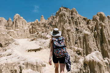 A tourist with a backpack and hat walks among the rocks in the Moon Valley of La Paz. Valle de la...