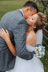 The bride and groom embrace. The bride gently hugs the groom by the shoulders. Beautiful wedding couple. The concept of romance in a newlyweds relationship. Honeymoon.