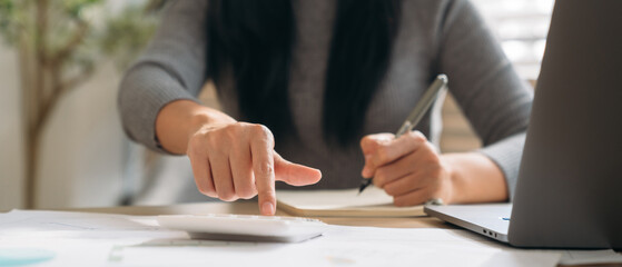 Close up hand of Business woman using laptop while plan and discussion information for financial in home office. Beautiful woman happy and working at indoors.