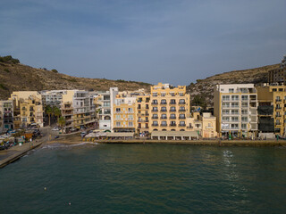 Xlendi hotels waterfront at Xlendi bay on a calm afternoon. Aerial view of traditional Saint...