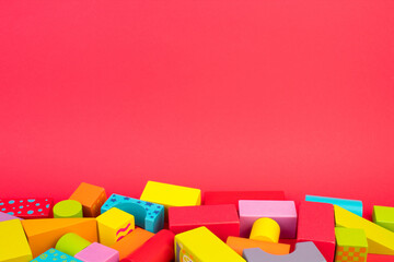 Top view of colorful wooden bricks on the table. Early learning. Educational toys on a red background. - obrazy, fototapety, plakaty